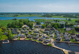 Aerial view of a holiday park offering glamping accommodations by a lake, set in a lush green landscape.