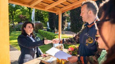 Huéspedes hacen el check-in en la recepción exterior de un parque vacacional con glamping.