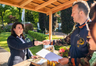 Gasten checken in aan een buitenbalie van een vakantiepark met glamping accommodaties.
