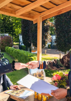 Guests check in at an outdoor reception desk in a holiday park offering glamping accommodations.