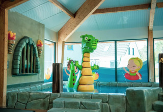 Innenbereich eines Ferienparks mit Drachen-Wasserfontäne und bunten kinderfreundlichen Dekorationen.