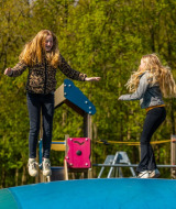 Dos niñas juegan y saltan sobre una gran almohada inflable en el parque infantil de un camping glamping.