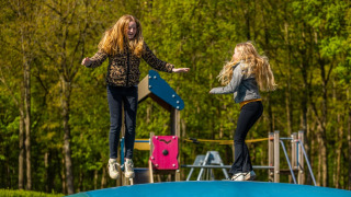 Dos niñas juegan y saltan sobre una gran almohada inflable en el parque infantil de un camping glamping.