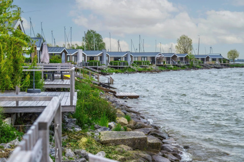 Cabañas glamping junto al lago en un parque vacacional, terrazas de madera y vistas pintorescas al agua.