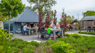Outdoor dining area at a holiday park offering glamping, families enjoying meals surrounded by greenery.
