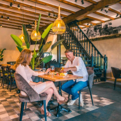 Ein Paar genießt eine Mahlzeit in einem stilvollen Restaurant eines Ferienparks mit Glamping-Angeboten.