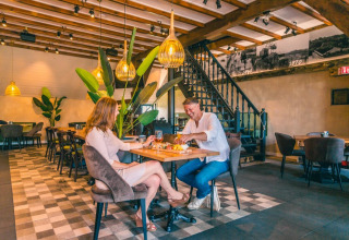 Pareja disfruta de una comida en un restaurante acogedor de un parque vacacional con glamping.