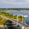 View of a bridge and scenic lake with modern glamping cabins in the background at a holiday park.
