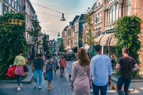 Personas pasean por una calle animada con tiendas y cafés cerca de un parque vacacional de glamping.