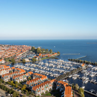 Vista aérea de un parque vacacional con marina y casas con tejados rojos, que ofrece glamping junto al agua.