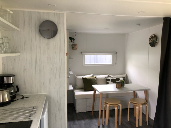 Vista interior de la tienda safari Coco Deluxe en Vakantiepark Delftse Hout con comedor y cocina pequeña.