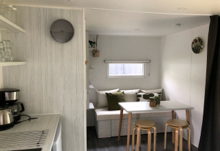 Vista interior de la tienda safari Coco Deluxe en Vakantiepark Delftse Hout con comedor y cocina pequeña.