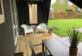 Terraza cubierta junto a la tienda safari Coco Deluxe en Vakantiepark Delftse Hout, con mobiliario moderno.