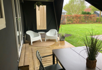 Terraza cubierta junto a la tienda safari Coco Deluxe en Vakantiepark Delftse Hout, con mobiliario moderno.