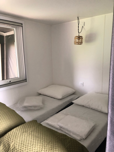 Intérieur d'une tente safari Coco Deluxe avec deux lits simples au Vakantiepark Delftse Hout, aux Pays-Bas.