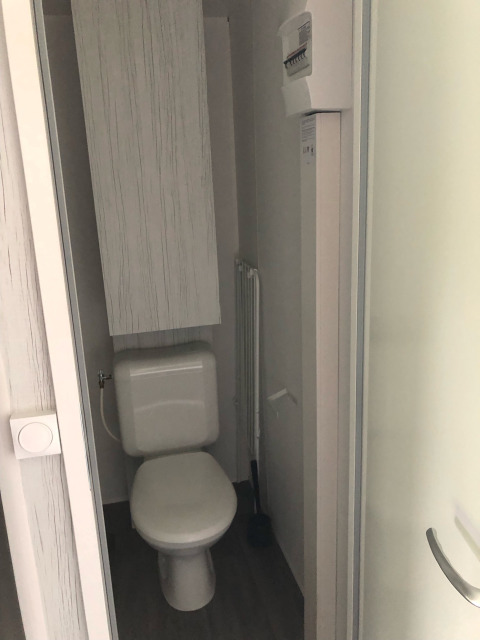 Pequeño baño con inodoro y panel eléctrico en tienda safari Coco Deluxe en Vakantiepark Delftse Hout.