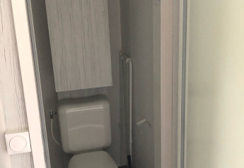 Pequeño baño con inodoro y panel eléctrico en tienda safari Coco Deluxe en Vakantiepark Delftse Hout.