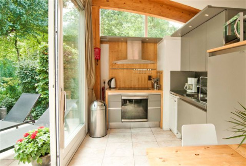 Pequeña cocina moderna con ventanales grandes y vista al jardín en Grasdakbungalow, parque Delftse Hout.