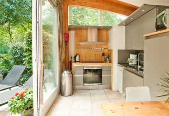 Kleine Küche mit moderner Ausstattung und großer Glasfront zum Garten im Grasdakbungalow in Delftse Hout.