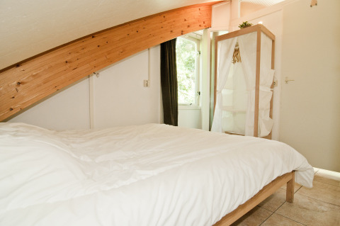 Slaapkamer in Grasdakbungalow met schuine houten balk bij Vakantiepark Delftse Hout, Nederland.