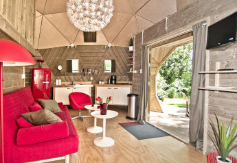Interiør af Wooden Igloo tiny house ved Holiday Park Delftse Hout med rød sofa og moderne køkken.