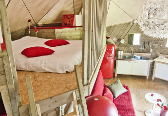 Indvendig udsigt af træigloen i Holiday Park Delftse Hout, Nederlandene, med røde møbler og hems.