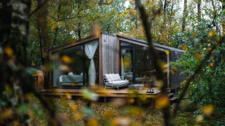 Cabaña moderna de madera llamada Cabin on the Hill en Wilsumer Berge, Alemania, rodeada de un bosque frondoso.
