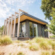 Moderne tiny house Beach lodge på Vakantiepark Leukermeer i Holland, omgivet af græs og træer.