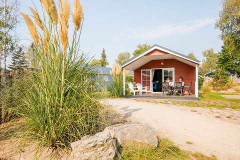 Familia disfruta del día soleado en el porche de una cabaña en Vakantiepark Leukermeer, Países Bajos.