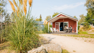 Gezin geniet op het terras van een lodge in Vakantiepark Leukermeer in Nederland van het mooie weer.