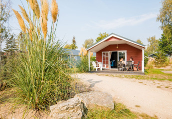 Familia disfruta del día soleado en el porche de una cabaña en Vakantiepark Leukermeer, Países Bajos.