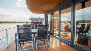 Vlot huis met houten terras en eettafel bij het water in Vakantiepark Leukermeer, Nederland, op een zonnige dag.