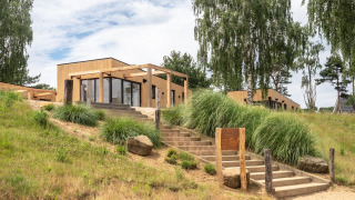 Moderne Beachlodge Deluxe in Vakantiepark Leukermeer, Nederland, met zand en groene natuur eromheen.
