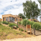 Moderne Beachlodge Deluxe på Vakantiepark Leukermeer, Holland, omgivet af sand og grønne træer.