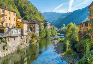 Zicht op kleurrijke huizen langs een rivier met groene bergen op de achtergrond bij Coreglia Antelminelli, Toscane.