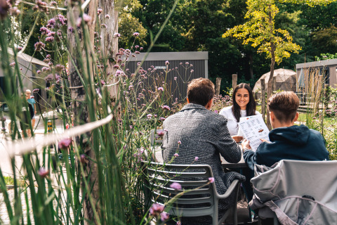Gasten dineren buiten tussen bloemen bij Vakantiepark Delftse Hout in Zuid-Holland, Nederland.