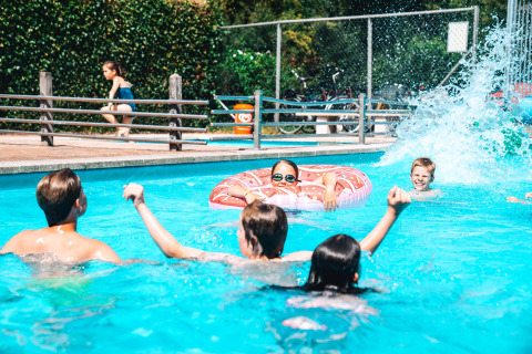 Kinderen spelen en zwemmen in het buitenzwembad van Vakantiepark Delftse Hout in Zuid-Holland, Nederland.