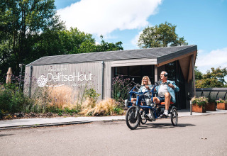 Twee mensen fietsen samen op een duofiets voor Vakantiepark Delftse Hout in Zuid-Holland, Nederland.