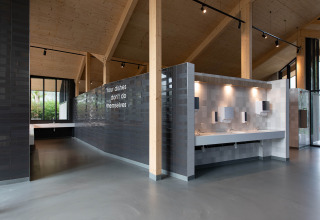 Modern communal dishwashing area at Vakantiepark Delftse Hout, Netherlands, with a playful wall message.