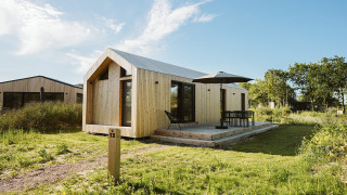 Moderne tiny house van hout met terras en parasol bij Holiday park De Klepperstee in Melle, Nederland.