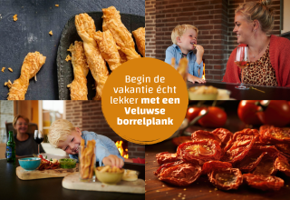 Gezin geniet van borrelhapjes aan tafel in glamping accommodatie, met kaasstengels en tomaten.