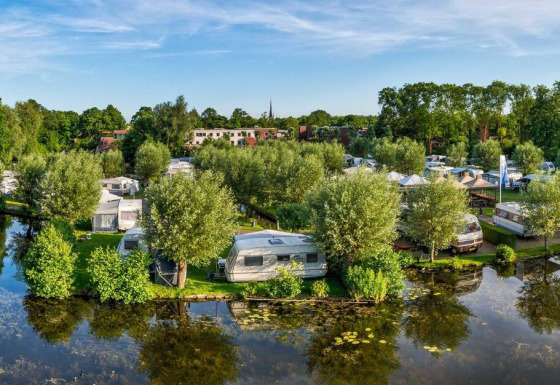 Panoramisch zicht op Camping Batenstein vakantiepark in Utrecht, Nederland, omringd door bomen en vijver.