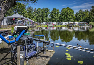Camping Batenstein in Utrecht, Nederland, met een vislijn aan het water en caravans achteraan.