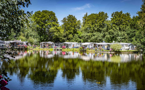 Caravanas y tiendas junto a un lago en Camping Batenstein, un parque vacacional en Utrecht, Países Bajos.