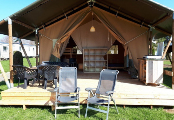 Safaritent op Camping Oos Heem in België met houten terras, tuinstoelen en buitentafel.