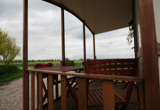 Blick von einer überdachten Holzterrasse bei Pipowagen auf Camping De Grienduil in den Niederlanden.