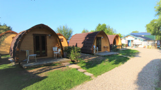 Pequeñas casas arqueadas en Camping De Grienduil, Países Bajos, ideales para una estancia tranquila.