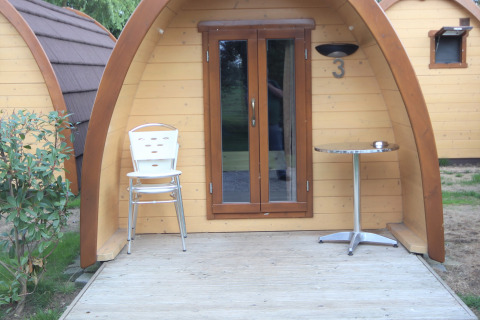 Entrance to Pod Traditional tiny house with chairs and table on terrace at Camping De Grienduil, Netherlands.