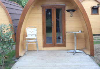 Indgang til et lille træhus, Pod Traditional, med stole og bord på terrassen, Camping De Grienduil, Holland.