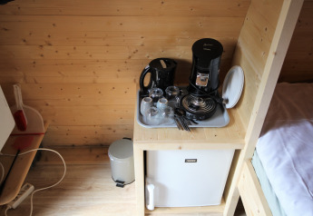 Coin cuisine dans Pod Traditional tiny house au Camping De Grienduil, Pays-Bas, avec bouilloire et mini-frigo.